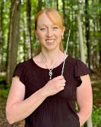 Woman holding baton standing in a forest