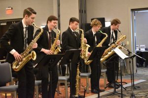 Five students standing and playing saxophones