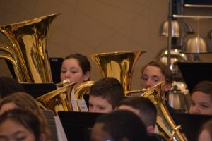 Two students sitting and playing tubas